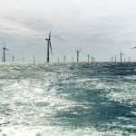 Wind farm seen across the sea on sunny day